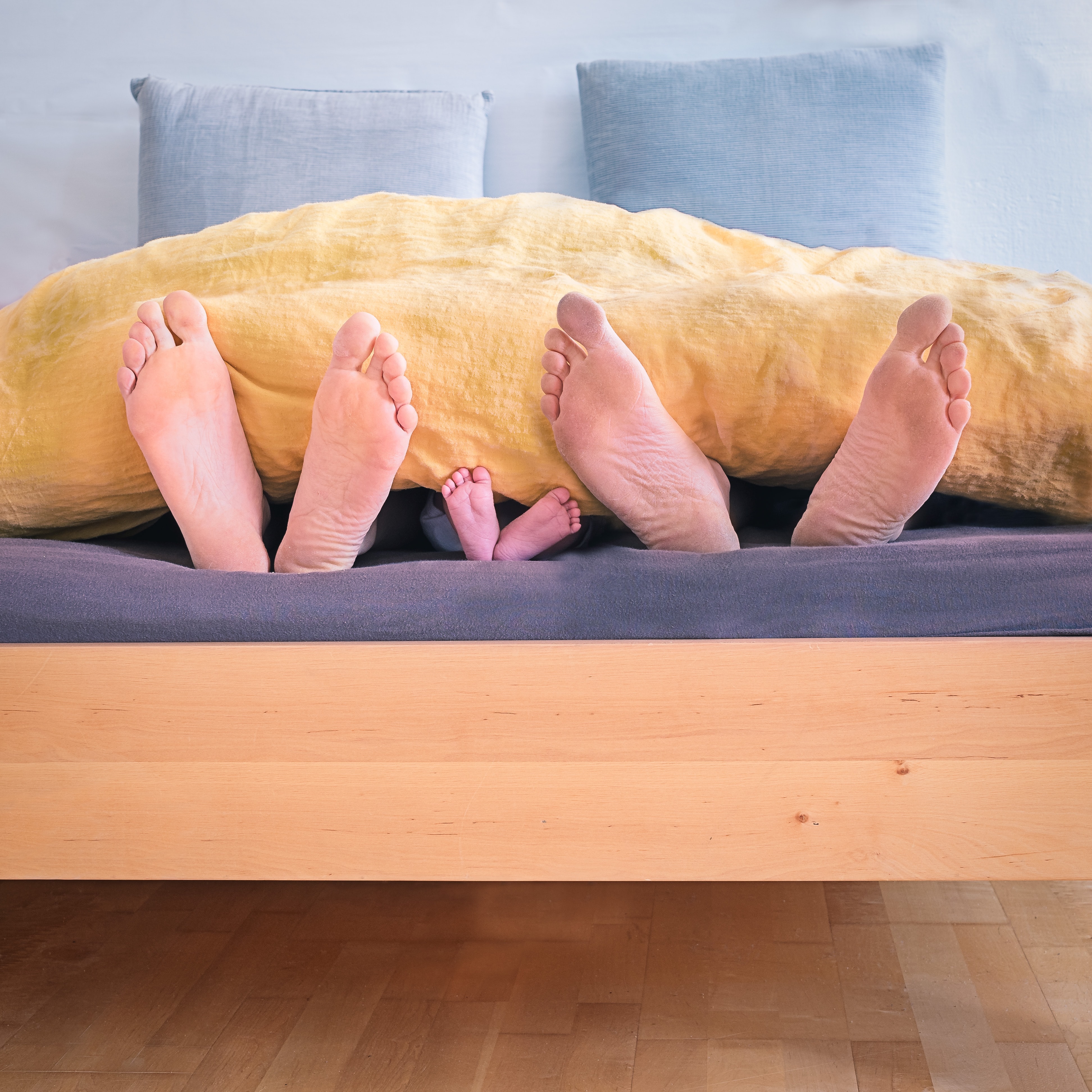 Füße einer Familie ragen aus einem Bett