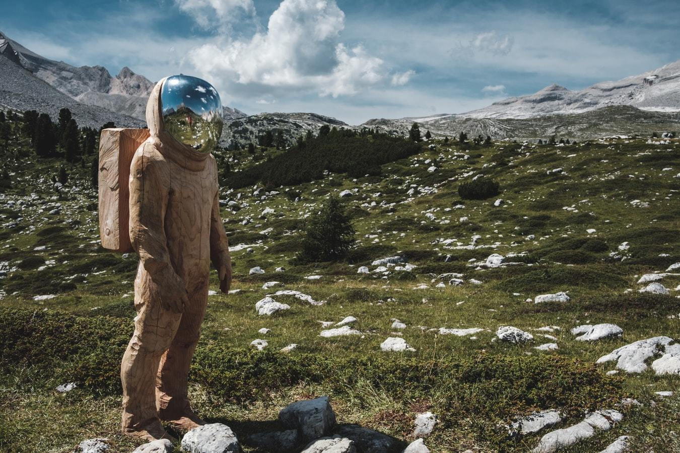 Astronaut aus Holz vor Alpenwiese mit Schnee