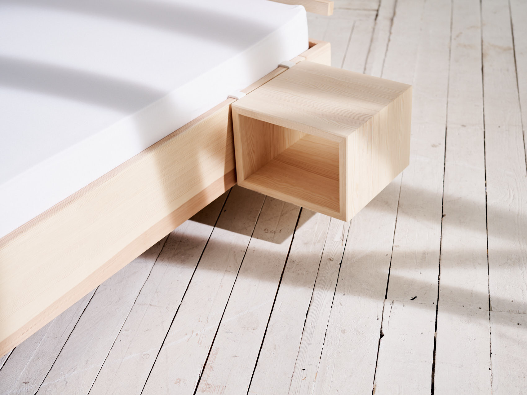 Massivholz Nachttisch schwebend auf weißem Holzboden mit Schatten