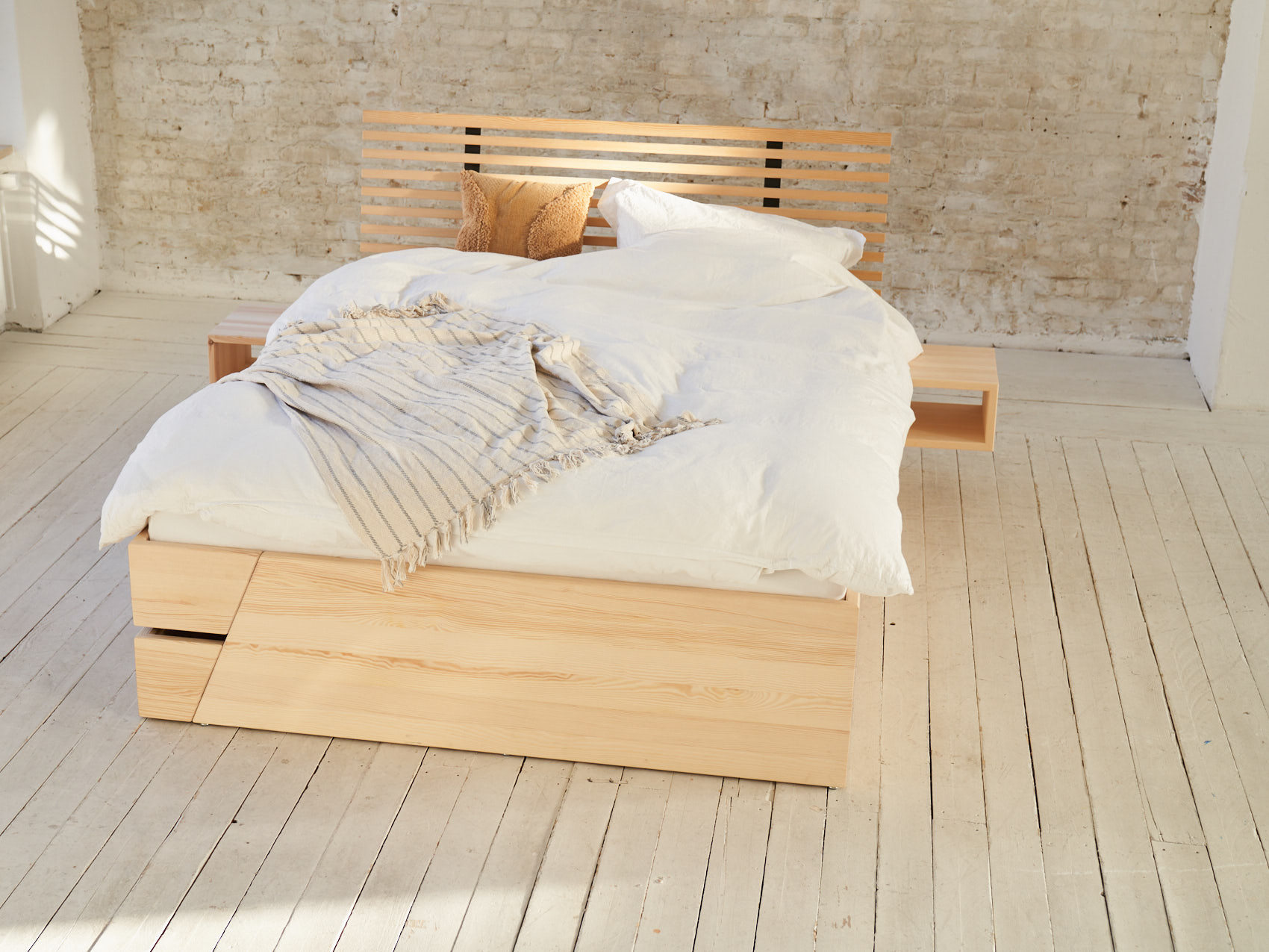 Massivholz Stauraumbett Kiezbett Schlafzimmer belebt im Raum auf Holzboden vor heller Backsteinwand